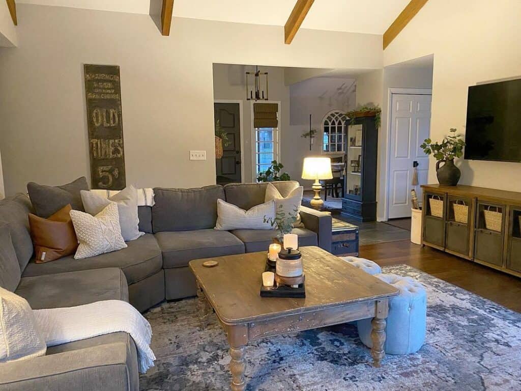Farmhouse living room with exposed wood beams on sloped ceiling and gray sectional next to rectangular coffee table
