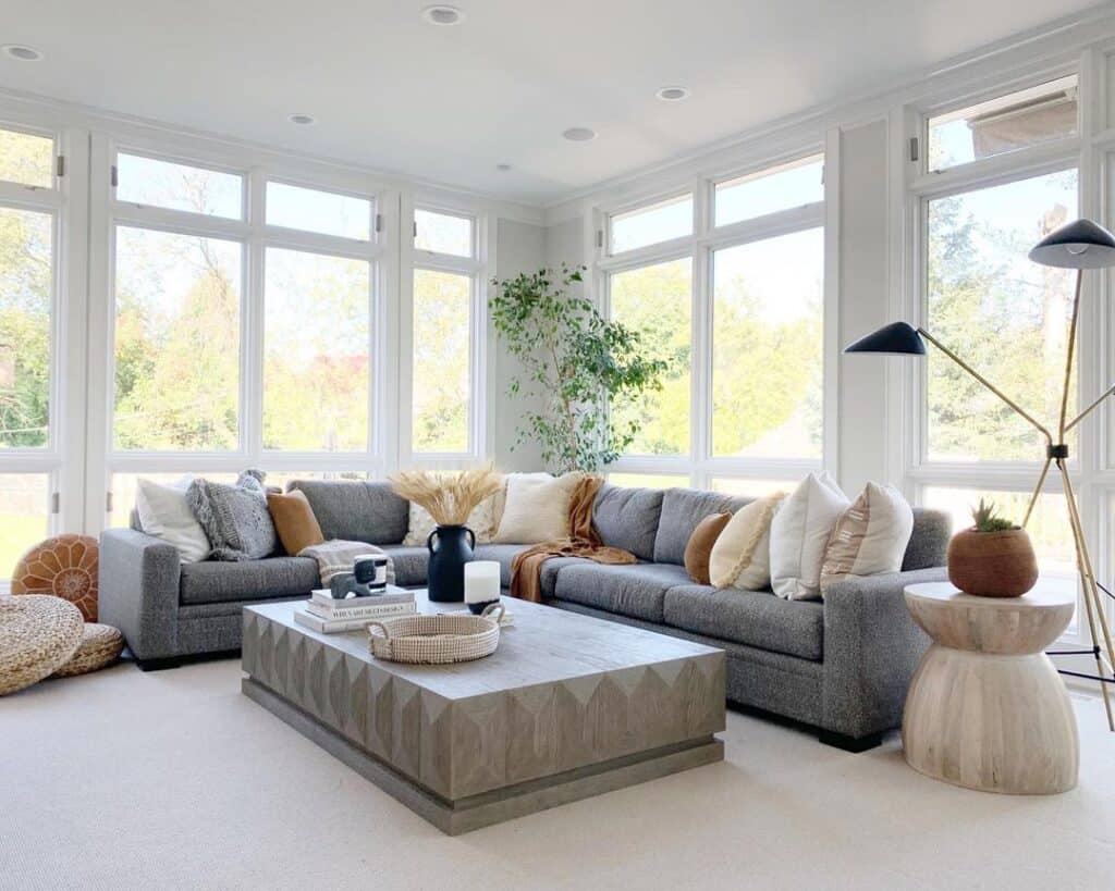 Grey sectional couch and a rectangular coffee table next to large windows in living room