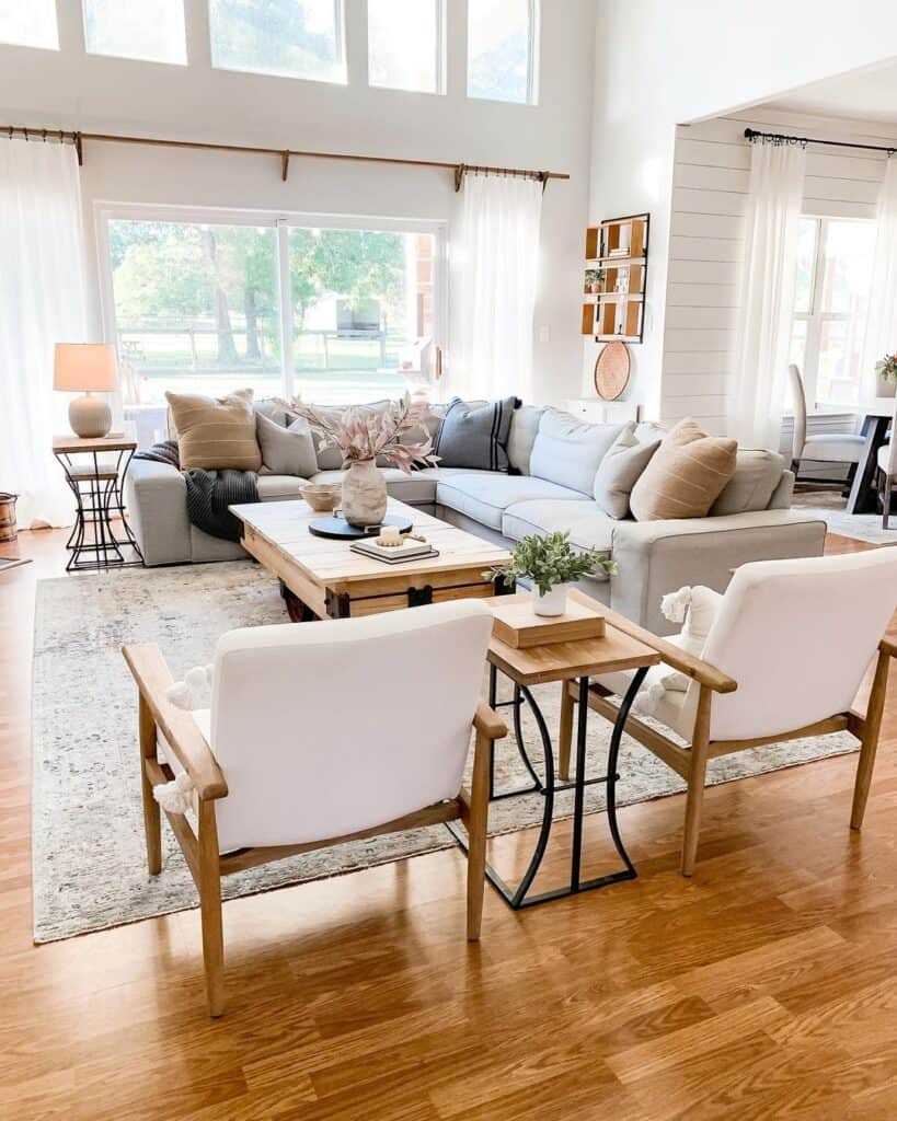 farmhouse living room with sectional next to coffee table surrounded by 2 wood and white chairs