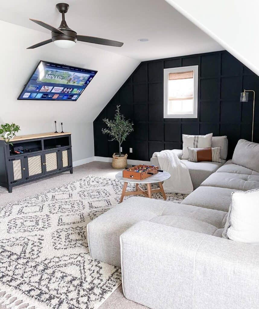 white and wood round coffee table with sectional sofa in living room with ceiling fan and black board and batten accent wall