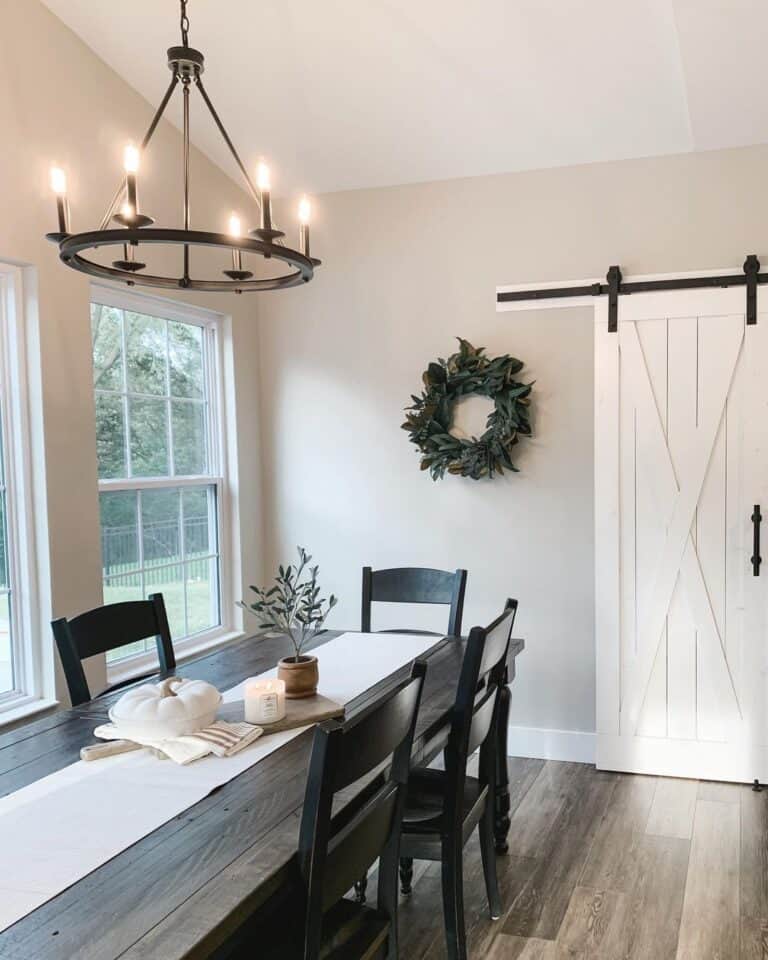 Dark wood rectangular dining table with black ladder back dining chairs in farmhouse dining room painted in SW Agreeable Gray