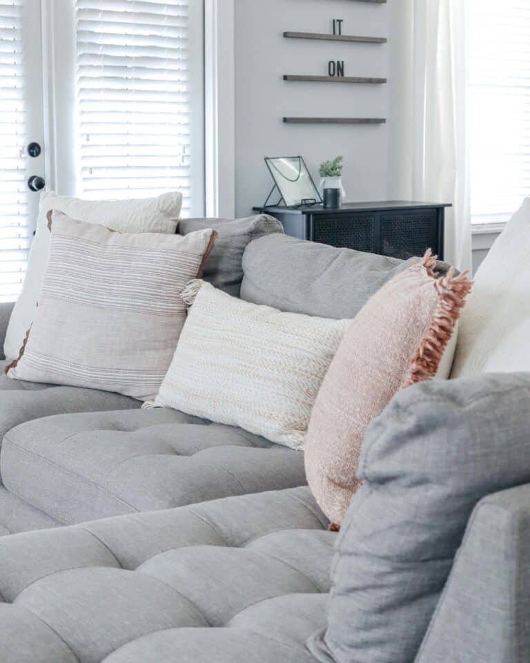 Grey Tufted Couch with White and Pale Red Throw Pillows Soul & Lane