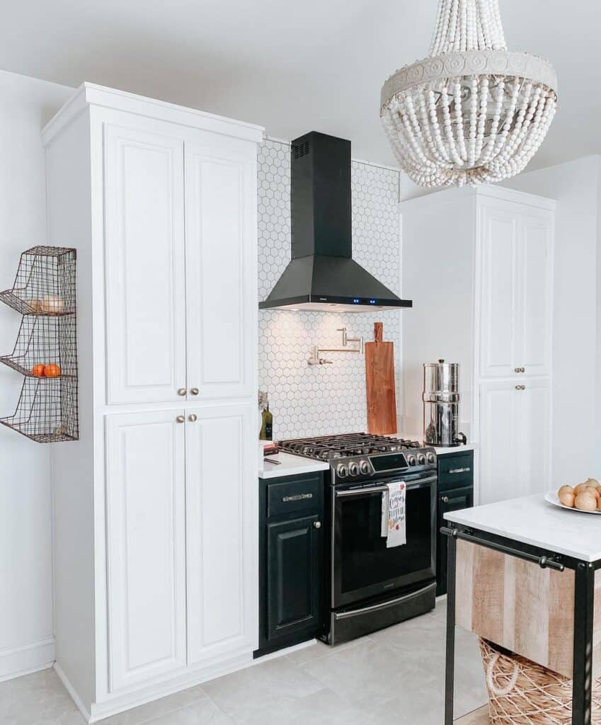 Black Hood and Stove Between Tall White Cabinets