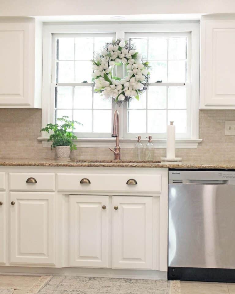 Flowered Wreath Over a Brass Kitchen Faucet