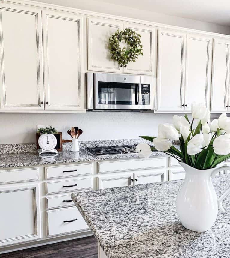Kitchen with White Flowers on Granite Countertop with Matching Backsplash