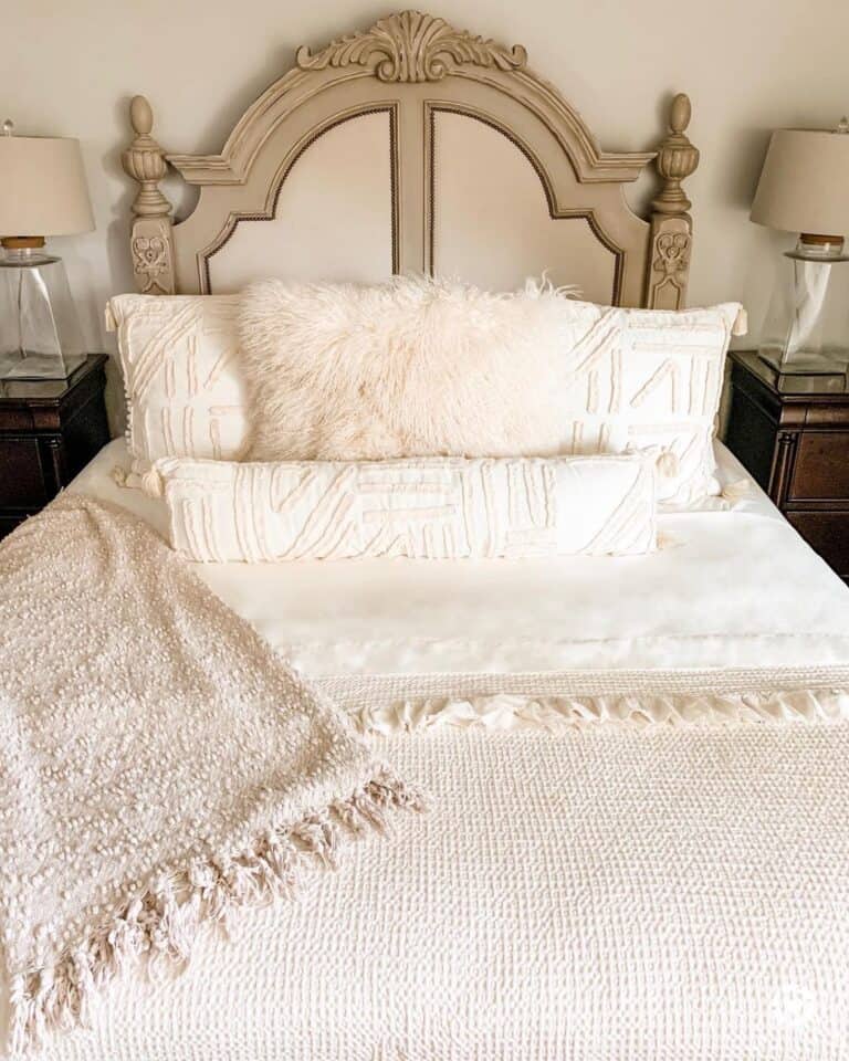 White Coverlet on Bed With Ornately Carved Wood Headboard