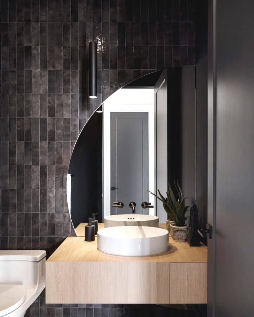 Black Tile Wall with Round Frameless Mirror