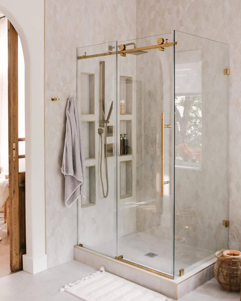 Brass Shower Head With a Home and Mosiac Tile Walls