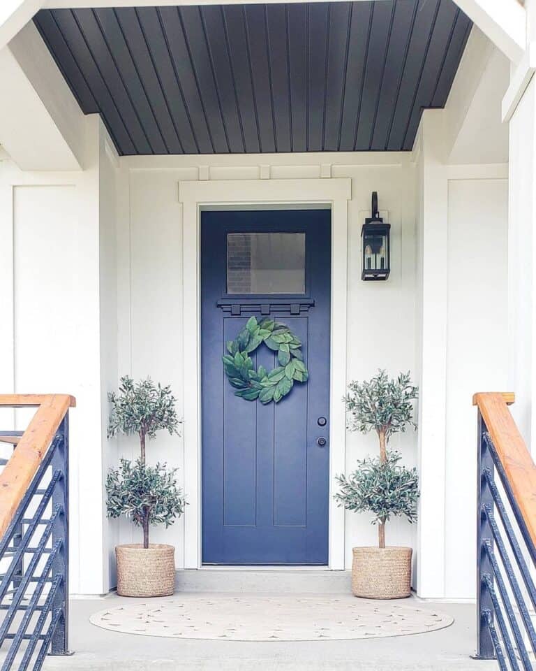 Dark Blue Door Next to a Pair of Small Olive Trees