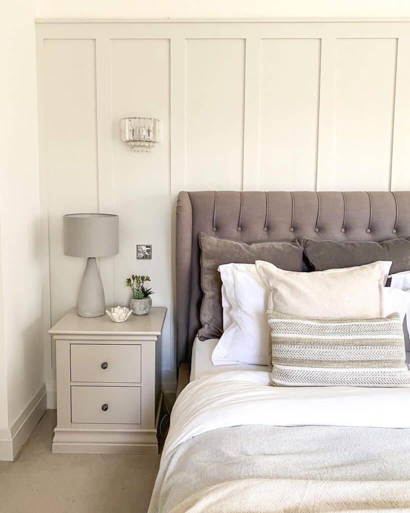 Gray Tufted Headboard Against Light Grey Wainscoting