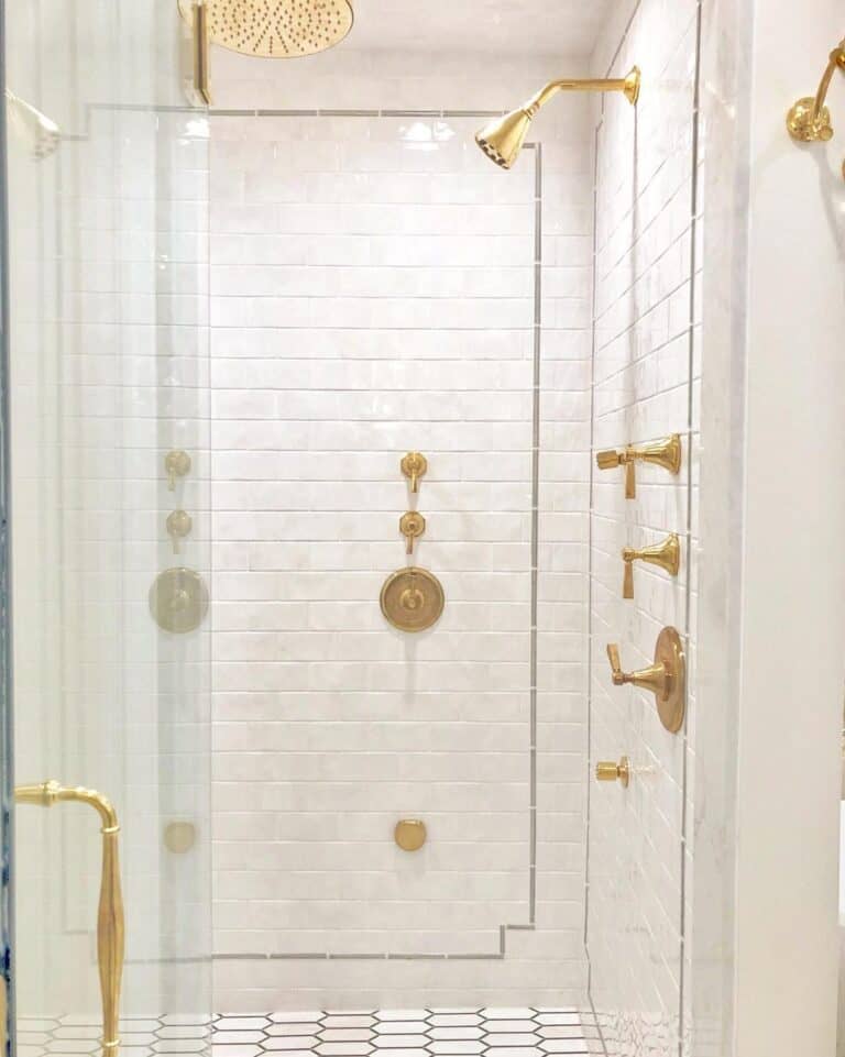 Polished Brass Shower Head on a White Tile Wall