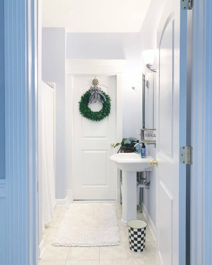 White Bathroom with Pedestal Sink and Green Wreath