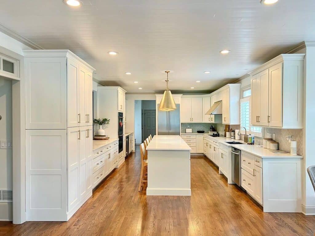 Warm Wood Flooring in White Cabinet Kitchen