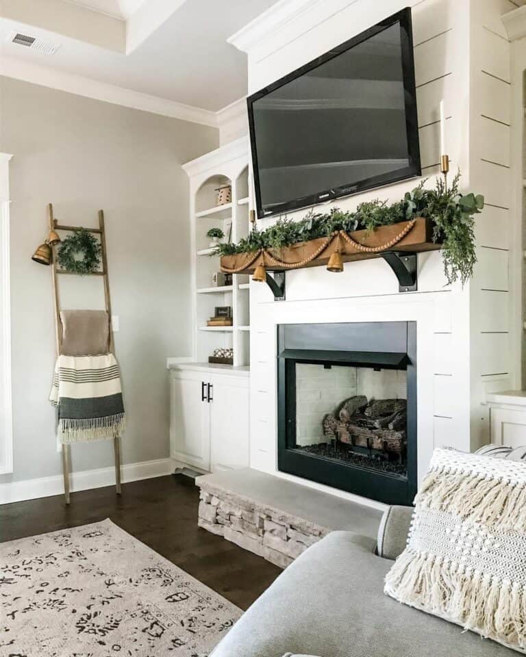 Green Garland and Brass Bells on a Wooden Mantel