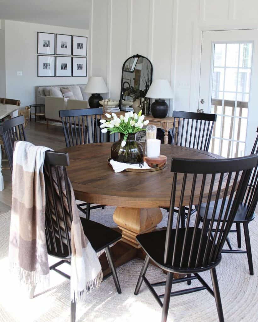 Round Wood Dining Table With Black Chairs and Bright Centerpiece