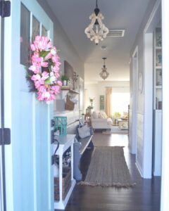 White Hallway Chandeliers and a Pink Tulip Wreath