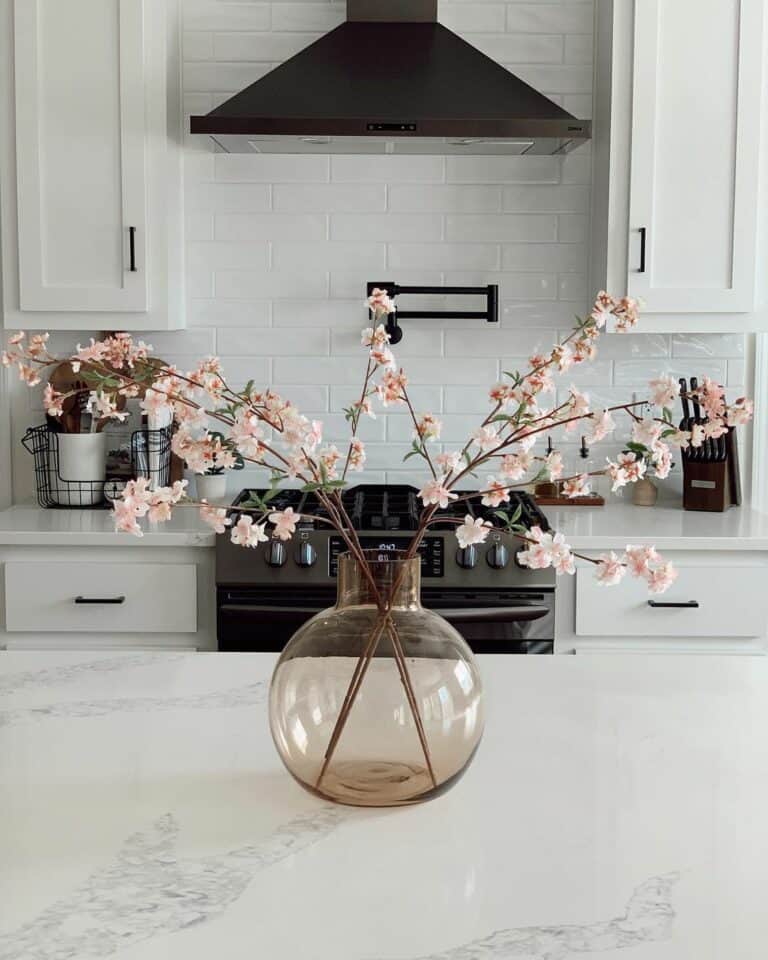 White Kitchen Island With a Pink Tinted Clear Glass Vase