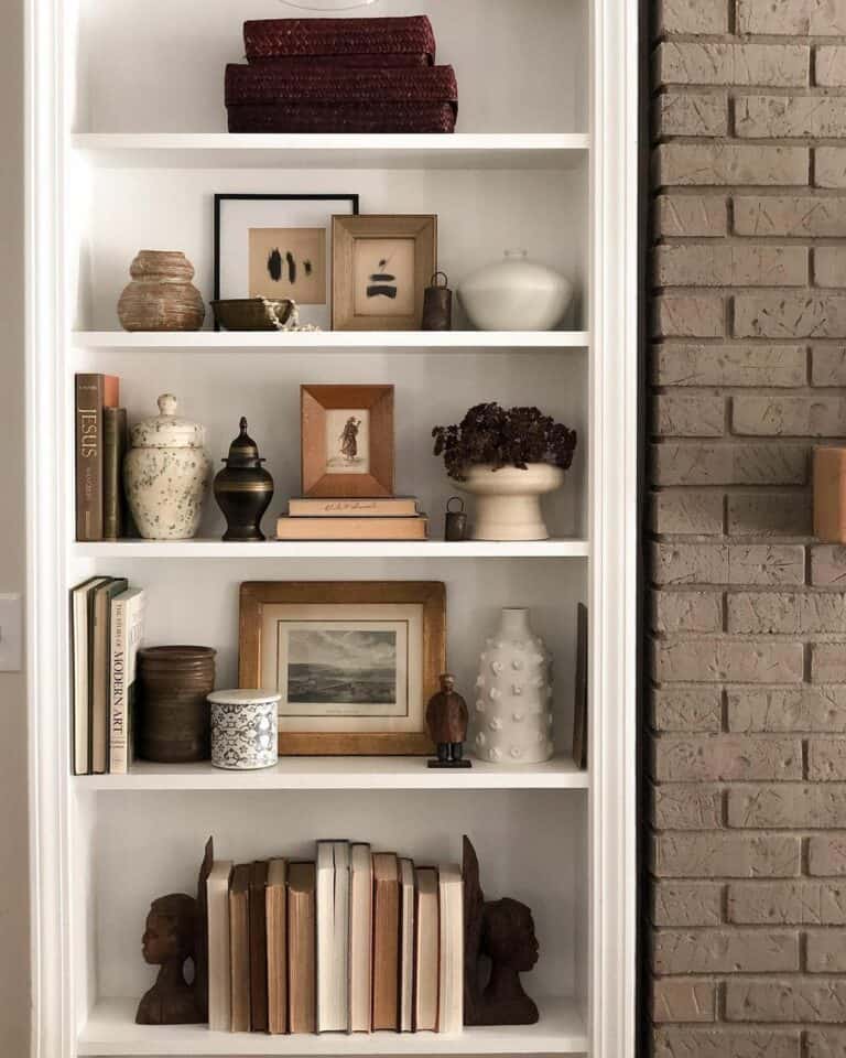 White Bookshelf Beside a Brick Wall