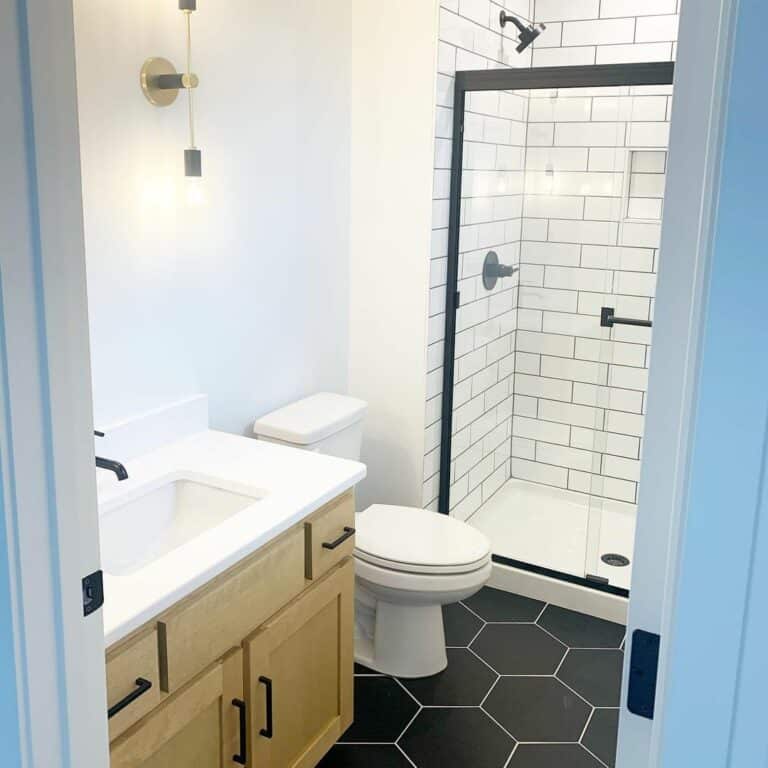 Bathroom With Light Wood Vanity and Black Hexagon Tiles